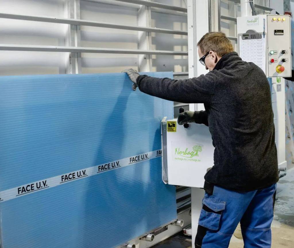 Worker is cutting multiwall polycarbonate sheets with vertical machine
