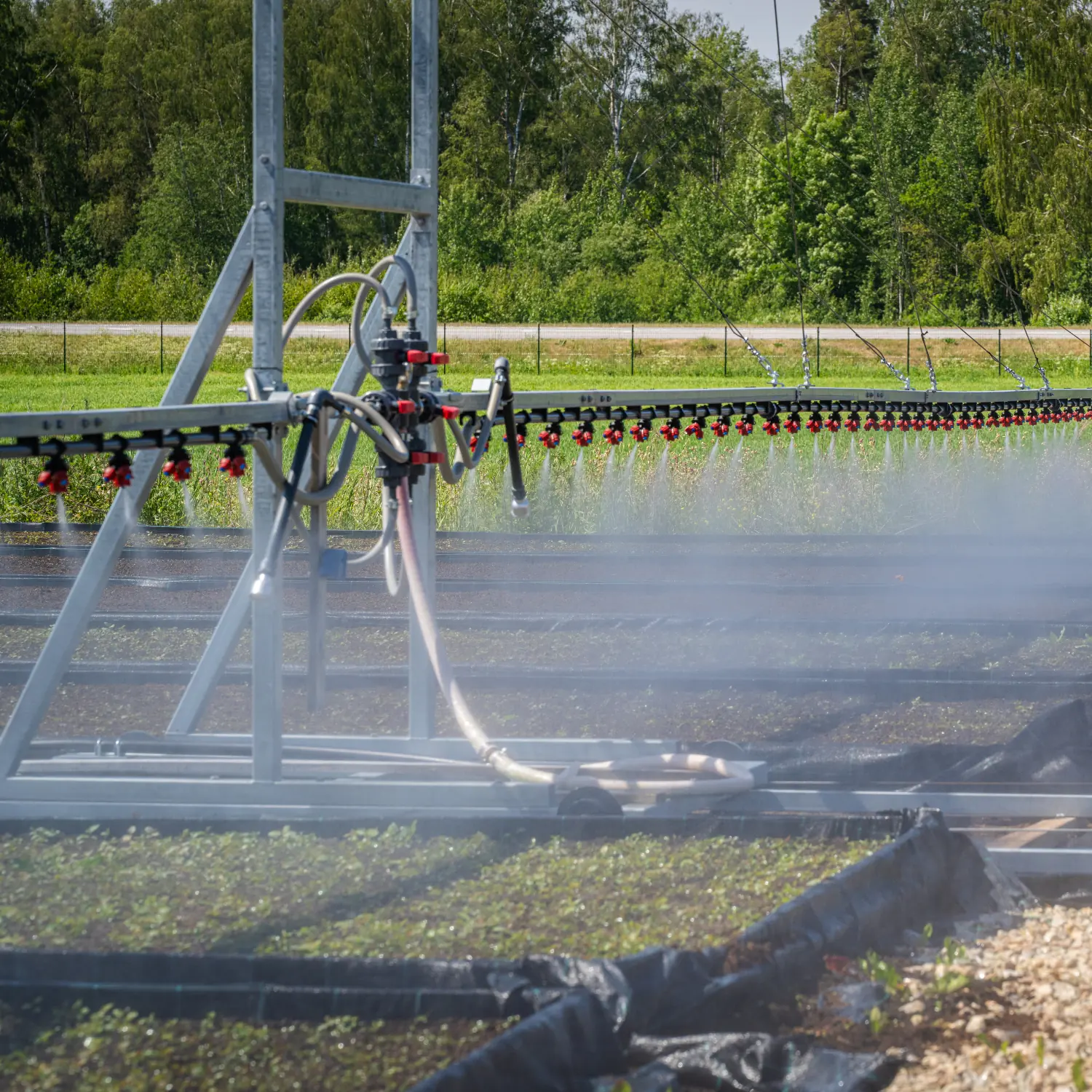 Outdoor irrigation boom spraying water evenly across crops in an open field