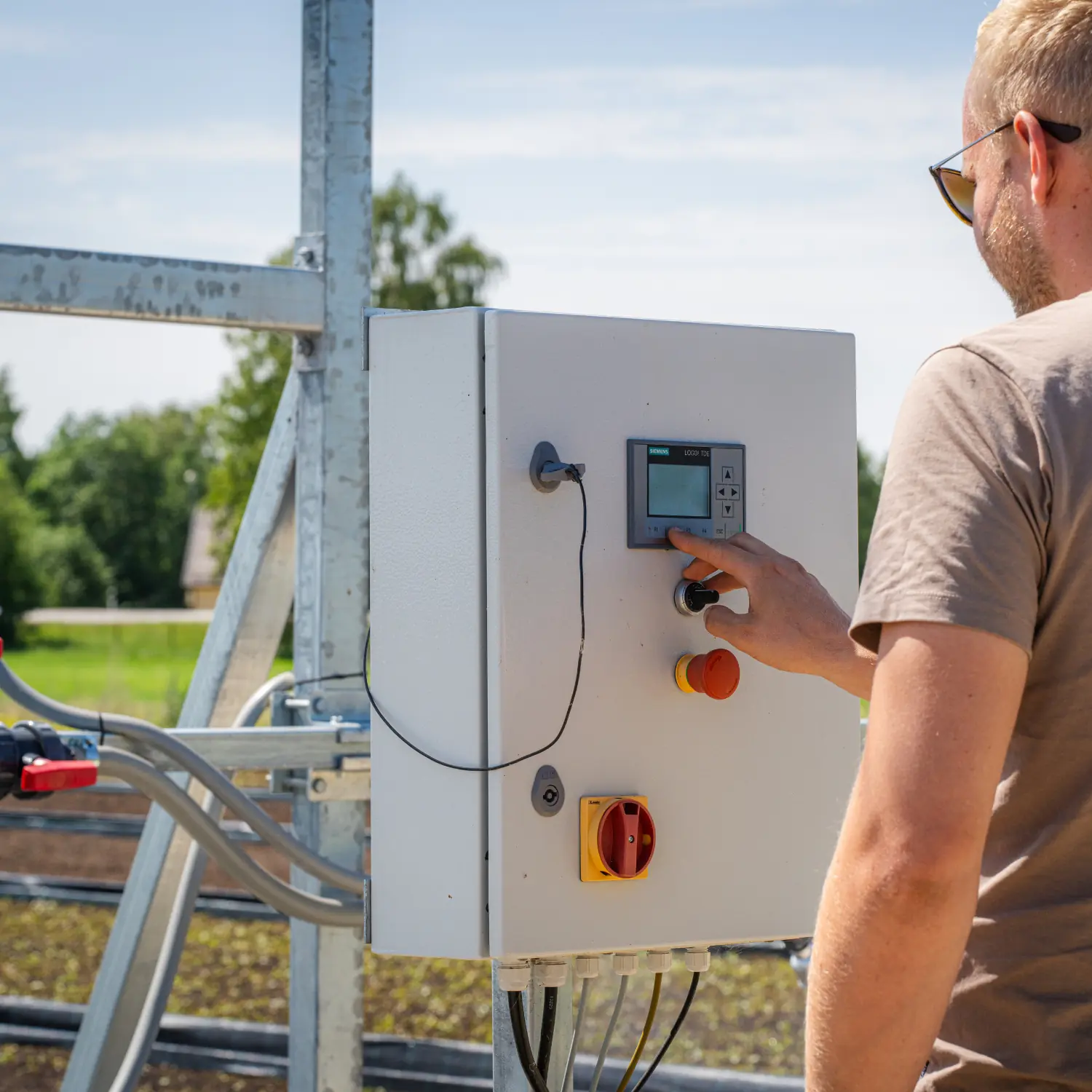 Worker inspecting and adjusting the irrigation boom control panel in the field